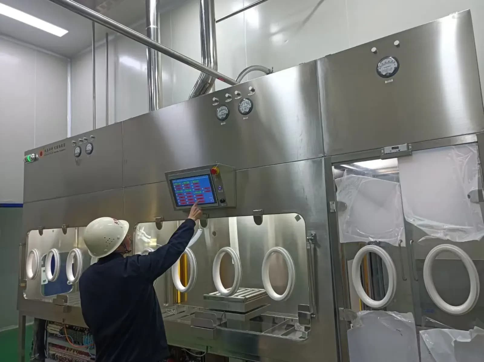 Operator using the control screen on an installed sterile test isolator
